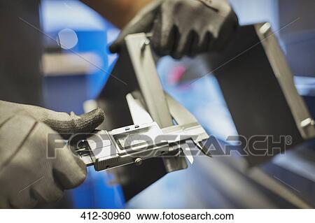 Stock Image - Worker measuring steel with calipers in steel factory. Fotosearch