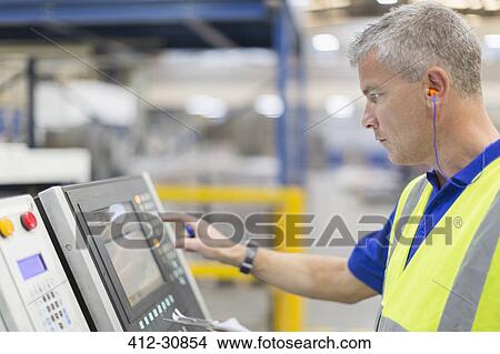 Worker operating machinery at control panel in steel factory View Large Photo Image Picture - Worker operating machinery at control panel in steel factory. Fotosearch
