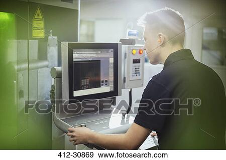 Stock Photo - Worker operating machinery at control panel in steel factory. Fotosearch