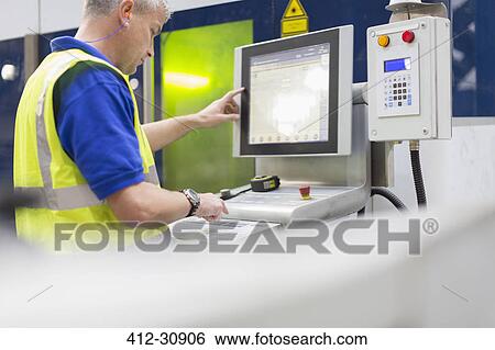 Worker operating machinery at control panel in steel factory View Large Photo Image Stock Photograph - Worker operating machinery at control panel in steel factory. Fotosearch