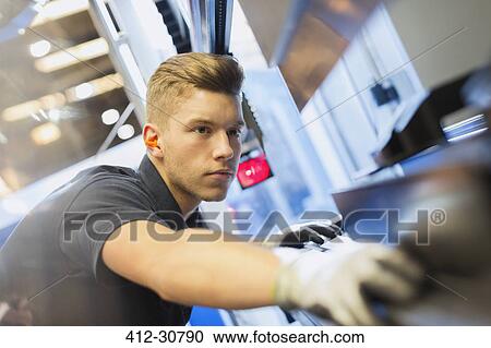 Stock Image - Worker operating machinery in steel factory. Fotosearch