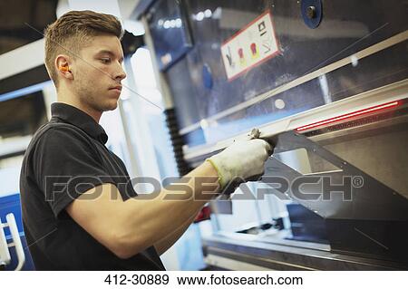 Stock Photo - Worker operating machinery in steel factory. Fotosearch