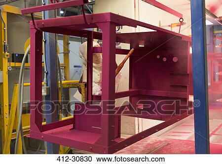Stock Image - Worker painting steel red in steel factory. Fotosearch