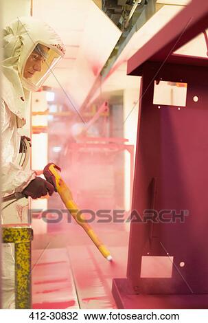 Stock Image - Worker painting steel red in steel factory. Fotosearch