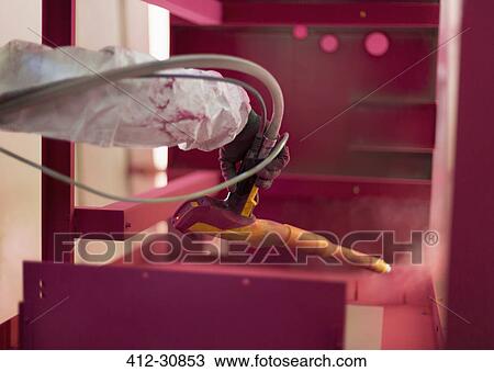 Stock Image - Worker painting steel red in steel factory. Fotosearch
