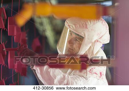 Stock Photograph - Worker painting steel red in steel factory. Fotosearch