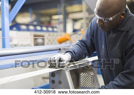 Stock Photo - Worker sanding steel in steel factory. Fotosearch