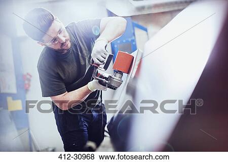 Stock Photo - Worker sanding steel in steel factory. Fotosearch
