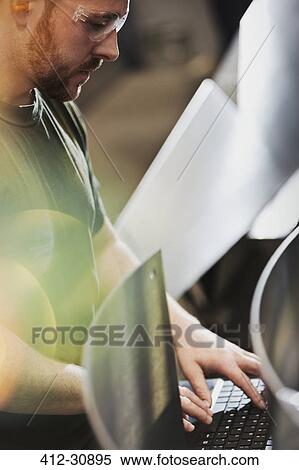 Worker using computer in steel factory View Large Photo Image Stock Photography - Worker using computer in steel factory. Fotosearch