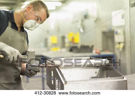 Stock Photo - Worker using equipment in steel factory. Fotosearch