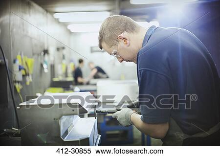 Stock Photography - Worker using machinery in steel factory. Fotosearch
