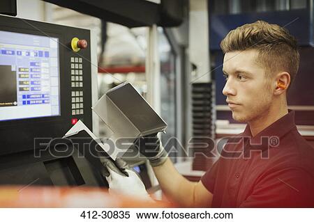 Stock Photography - Worker with part at control panel in steel factory. Fotosearch