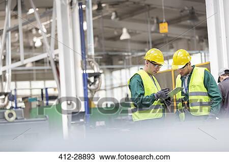 Workers in protective workwear talking with clipboard working in factory View Large Photo Image Stock Image - Workers in protective workwear talking with clipboard working in factory. Fotosearch