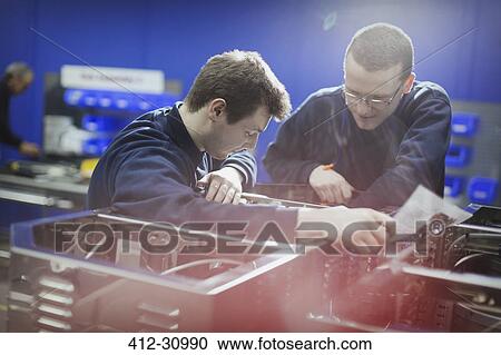 Stock Image - Workers inspecting machinery in steel factory. Fotosearch