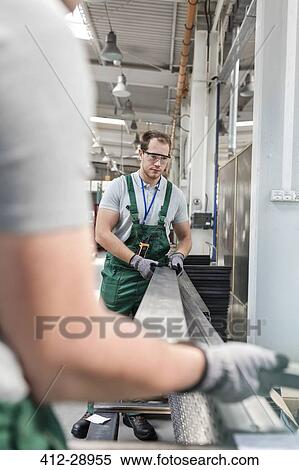 Workers lifting metal parts in factory View Large Photo Image Stock Photography - Workers lifting metal parts in factory. Fotosearch