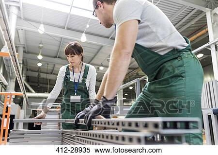 Stock Photography - Workers moving steel parts in factory. Fotosearch