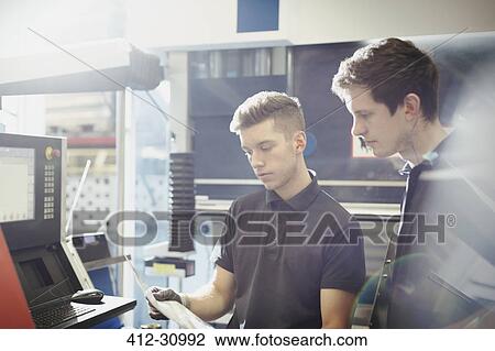 Workers reviewing paperwork at machinery control panel in steel factory View Large Photo Image Stock Image - Workers reviewing paperwork at machinery control panel in steel factory. Fotosearch