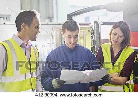 Workers reviewing paperwork in steel factory View Large Photo Image Picture - Workers reviewing paperwork in steel factory. Fotosearch