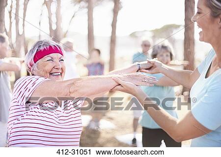 Yoga instructor guiding senior woman in park View Large Photo Image Stock Image - Yoga instructor guiding senior woman in park. Fotosearch