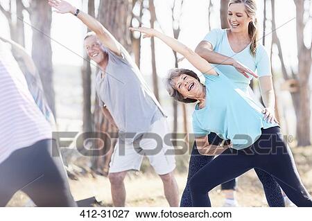 Yoga instructor guiding senior woman in park View Large Photo Image Stock Photo - Yoga instructor guiding senior woman in park. Fotosearch