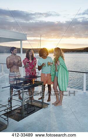 Young adult friends barbecuing, hanging out and drinking on summer houseboat at sunset View Large Photo Image Stock Photo - Young adult friends barbecuing, hanging out and drinking on summer houseboat at sunset. Fotosearch