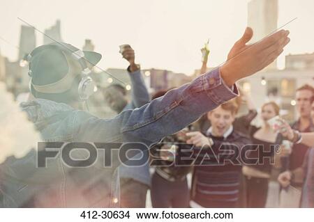Young adult friends cheering for DJ at rooftop party View Large Photo Image Picture - Young adult friends cheering for DJ at rooftop party. Fotosearch