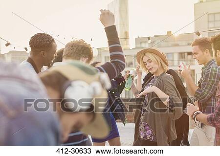 Young adult friends dancing at rooftop party View Large Photo Image Stock Image - Young adult friends dancing at rooftop party. Fotosearch
