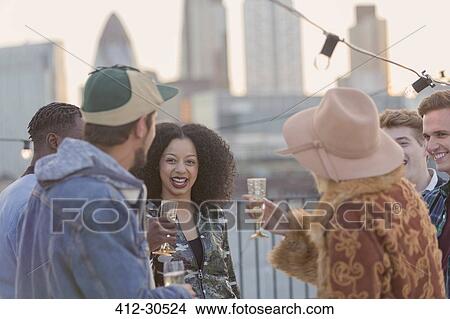 Young adult friends drinking champagne at rooftop party View Large Photo Image Picture - Young adult friends drinking champagne at rooftop party. Fotosearch