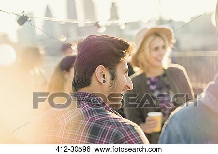 Young adult friends enjoying rooftop party View Large Photo Image Stock Photograph - Young adult friends enjoying rooftop party. Fotosearch