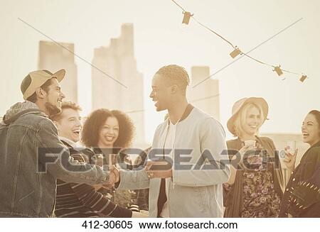 Young adult friends handshaking at rooftop party View Large Photo Image Stock Photography - Young adult friends handshaking at rooftop party. Fotosearch