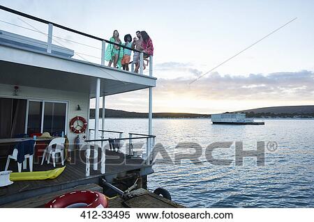 Young adult friends hanging out on deck of summer houseboat on ocean View Large Photo Image Stock Photography - Young adult friends hanging out on deck of summer houseboat on ocean. Fotosearch