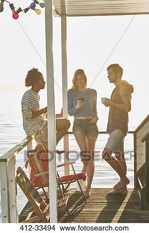 Young adult friends hanging out on sunny summer houseboat View Large Photo Image Picture - Young adult friends hanging out on sunny summer houseboat. Fotosearch