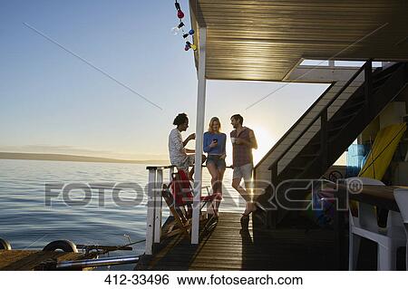 Stock Photograph - Young adult friends hanging out on summer houseboat on ocean. Fotosearch