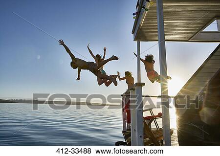 Young adult friends jumping from summer houseboat into sunny ocean View Large Photo Image Stock Photo - Young adult friends jumping from summer houseboat into sunny ocean. Fotosearch
