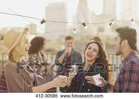 Young adult friends laughing and drinking at rooftop party View Large Photo Image Stock Photography - Young adult friends laughing and drinking at rooftop party. Fotosearch