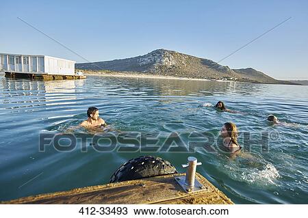 Stock Image - Young adult friends swimming in sunny summer ocean. Fotosearch