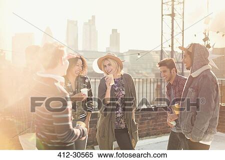 Young adult friends talking and drinking at rooftop party View Large Photo Image Stock Photography - Young adult friends talking and drinking at rooftop party. Fotosearch