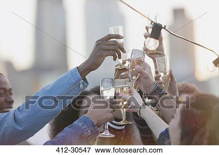 Young adult friends toasting champagne flutes at party View Large Photo Image Stock Photo - Young adult friends toasting champagne flutes at party. Fotosearch