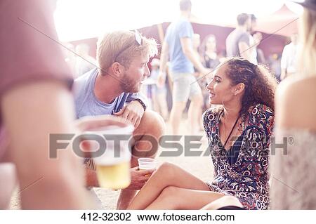 Young couple drinking beer and talking at music festival View Large Photo Image Stock Image - Young couple drinking beer and talking at music festival. Fotosearch