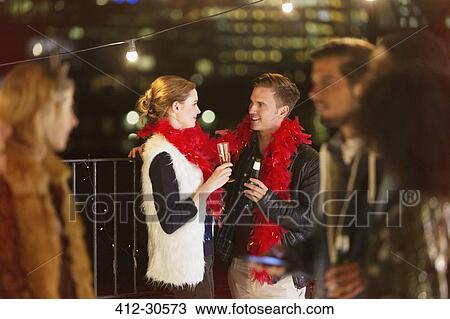 Young couple drinking champagne at nighttime rooftop party View Large Photo Image Stock Image - Young couple drinking champagne at nighttime rooftop party. Fotosearch