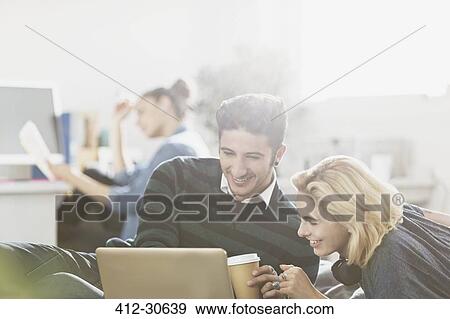 Young couple drinking coffee and using laptop View Large Photo Image Stock Photo - Young couple drinking coffee and using laptop. Fotosearch