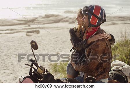 Young couple hugging at motorcycle looking at ocean view View Large Photo Image Stock Photo - Young couple hugging at motorcycle looking at ocean view. Fotosearch
