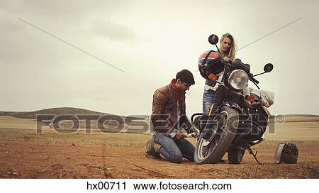 Young couple repairing motorcycle in remote countryside field View Large Photo Image Stock Image - Young couple repairing motorcycle in remote countryside field. Fotosearch