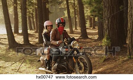 Stock Photo - Young couple riding motorcycle in woods. Fotosearch