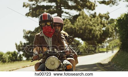 Young couple riding motorcycle on sunny road View Large Photo Image Stock Image - Young couple riding motorcycle on sunny road. Fotosearch