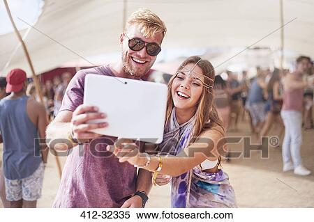 Stock Photography - Young couple taking selfie with digital tablet at music festival. Fotosearch