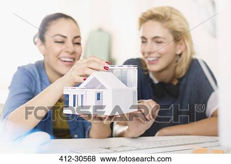 Young female architects assembling house model View Large Photo Image Stock Photo - Young female architects assembling house model. Fotosearch