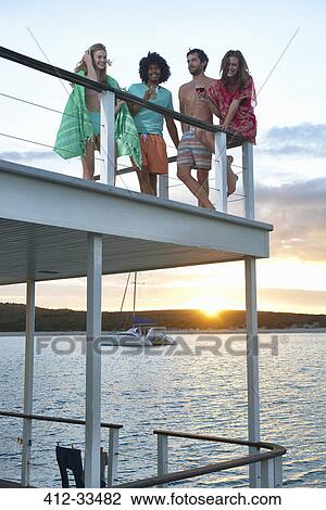Young friends hanging out and drinking on summer houseboat at sunset View Large Photo Image Stock Image - Young friends hanging out and drinking on summer houseboat at sunset. Fotosearch