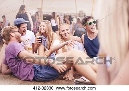 Young friends hanging out drinking and talking at music festival View Large Photo Image Stock Image - Young friends hanging out drinking and talking at music festival. Fotosearch