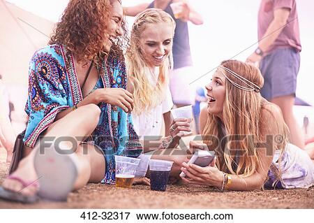 Young friends hanging out drinking and texting at music festival View Large Photo Image Stock Photo - Young friends hanging out drinking and texting at music festival. Fotosearch
